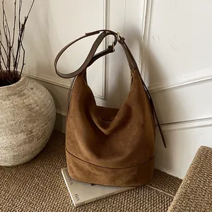 Brown suede hobo bag with adjustable leather strap in a minimalist indoor setting