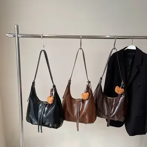 Three minimalist crescent shoulder bags in black and brown with plush bear charms