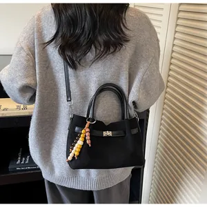Detalle de bolso negro texturizado con cierre giratorio y borla de cuentas de colores