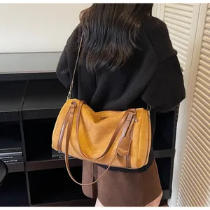 Detail of suede Boston bag in mustard yellow with brown leather handles on shoulder