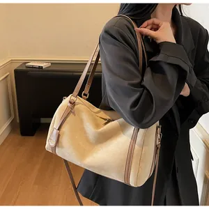 Detail view of large beige suede Boston bag with brown leather trim and sturdy handles