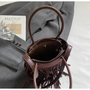 Détail d'un sac à main en cuir marron foncé avec franges et intérieur spacieux