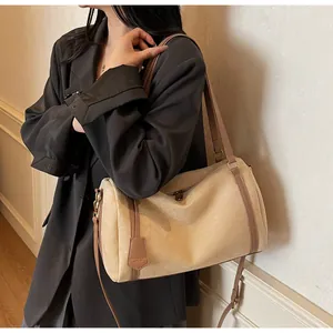 Close-up of beige suede Boston bag with brown leather handles and gold-tone hardware detail
