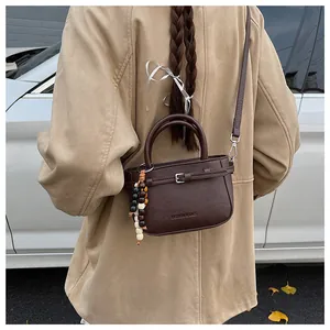 Detail of a dark brown leather mini bag with wooden bead charm and adjustable strap