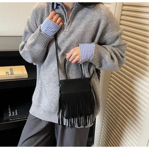 Vue détaillée d'un sac seau noir à longues franges avec bandoulière porté par un mannequin