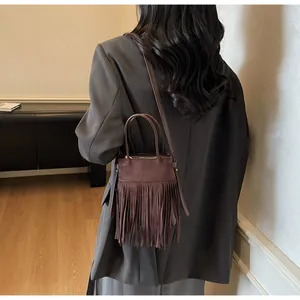Vue détaillée du sac seau marron foncé en daim avec de longues franges et bandoulière