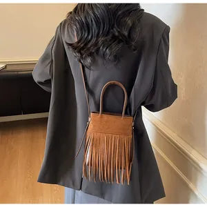 Vue détaillée du mannequin portant un sac bandoulière en daim marron avec franges