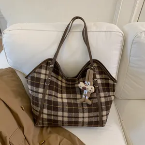 Détail d'un sac cabas à carreaux vintage avec lanières en cuir et un pendentif lapin