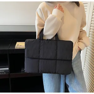 Detail of black quilted laptop tote bag showing the soft texture and large square stitching