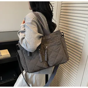 Detail of grey quilted tote bag featuring multiple zipper pockets and woven cord accents