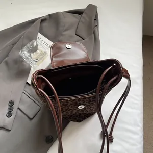 Minimalist leopard print bucket shoulder bag with brown leather straps and magnetic closure