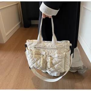 Detail of off-white quilted tote bag with multi-zipper pockets and woven cord pulls