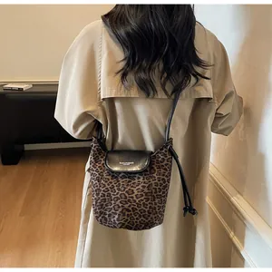 Detail of leopard print bucket bag with leather flap and adjustable strap on model