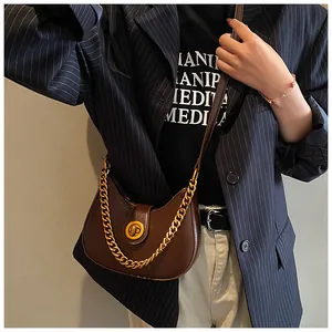 Detail of vintage dark brown crescent bag with gold chain and metal twist lock