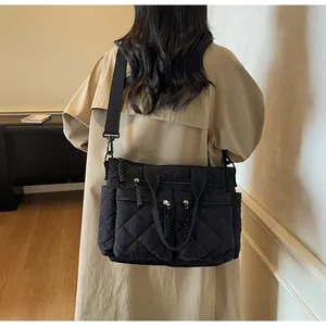 Detail of black quilted shoulder bag featuring multiple functional zippers and woven cords
