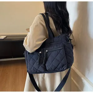 Detail of quilted large tote bag featuring symmetric zip pockets and woven pullers