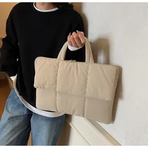 Close-up of beige quilted tote bag showing padded stitching and smooth top zipper detail