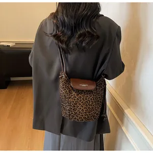 Detail of leopard print crossbody bag featuring a brown leather flap and magnetic closure