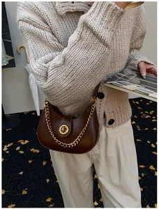 Close-up of retro dark brown crescent bag with gold chain and metal lock buckle