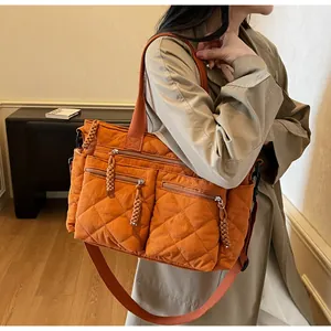 Detail view of large orange quilted tote bag with multi-pockets shown on model