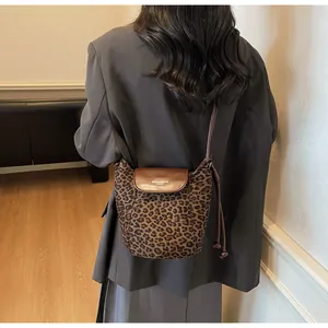 Detail of leopard print bucket bag with brown leather strap worn by a model