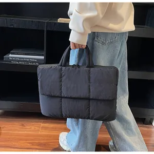 Dettaglio della borsa tote trapuntata nera con texture imbottita e doppi manici neri