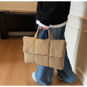 Dettaglio della borsa shopper trapuntata kaki tenuta da una modella in un interno accogliente