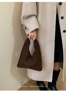Detail of minimalist dark brown suede handbag styled with a beige wool coat for commute