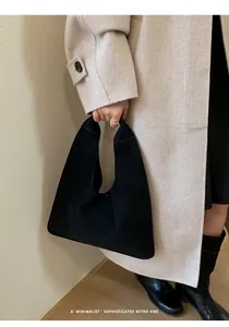 Detail of minimalist black suede handbag showcasing smooth matte texture and retro style