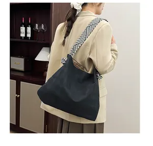 Detail of black woven tote bag with textured diamond pattern and striped shoulder strap