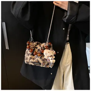 Detail of leopard print plush bag with gold chain strap and bead handle on a model