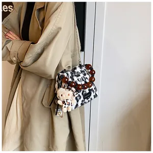 Detail of leopard plush bag with amber beaded handle and chain strap on trench coat