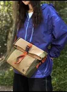 Outdoor crossbody messenger bag with khaki flap and orange strap in natural setting