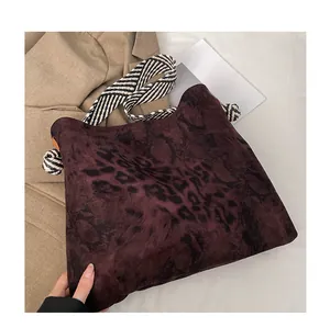 Close-up of leopard print tote bag with stylish wide striped strap and knotted detail
