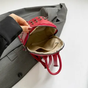 Red PU leather mini backpack with silver rivets showing internal pockets and zippers