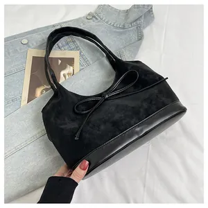 Detail of vintage black suede bucket bag with decorative bow and smooth leather textures
