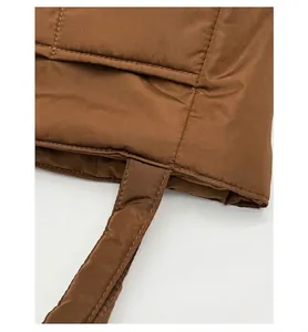 Close-up of the reinforced shoulder strap stitching on a dark brown quilted tote bag