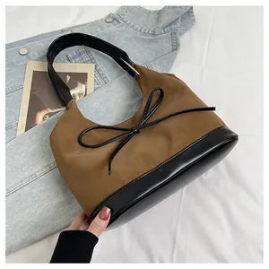 Detail view of brown hobo bag with black leather trim and delicate bow knot accent