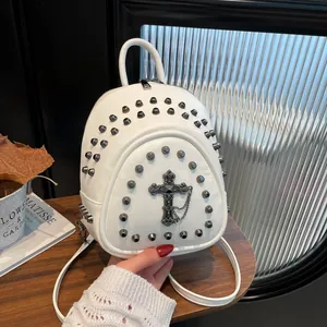 White mini backpack with metal rivets and a gothic cross pendant on a wooden surface