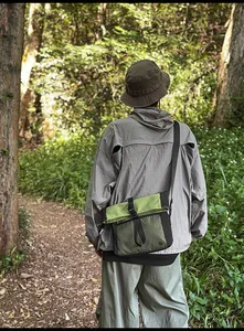 Outdoor crossbody bag shown with technical jacket and cargo pants in forest setting