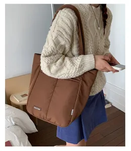 Detailed close-up of dark brown quilted tote bag with white logo label and soft texture