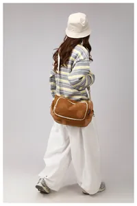 Brown nylon crossbody bag with white piping and wide strap shown on a model's back