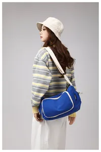 Side view of a blue nylon crossbody bag with white piping and beige strap on a model