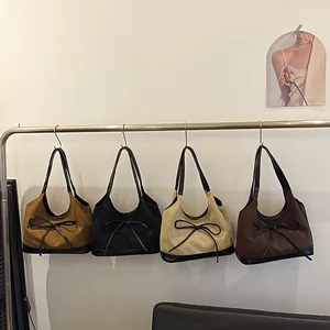 Retro suede hobo shoulder bags in four colors with leather bow detail on white backdrop