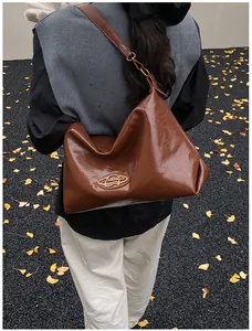 Sac bandoulière en cuir ciré marron porté par un mannequin en décor automnal