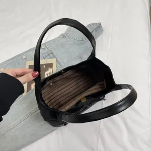 Minimalist black faux leather underarm bucket bag with striped lining and magnetic closure