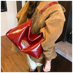 Détail du grand sac bandoulière en cuir verni bordeaux avec boucle dorée élégante