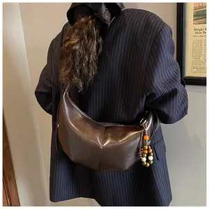 Detail of coffee brown crescent bag with colorful beaded charm on a striped blazer