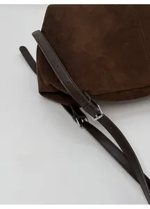 Detail of adjustable shoulder strap buckle on dark brown suede leather tote bag