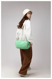 Side view of a bright green nylon crossbody bag with white zipper trim on female model
